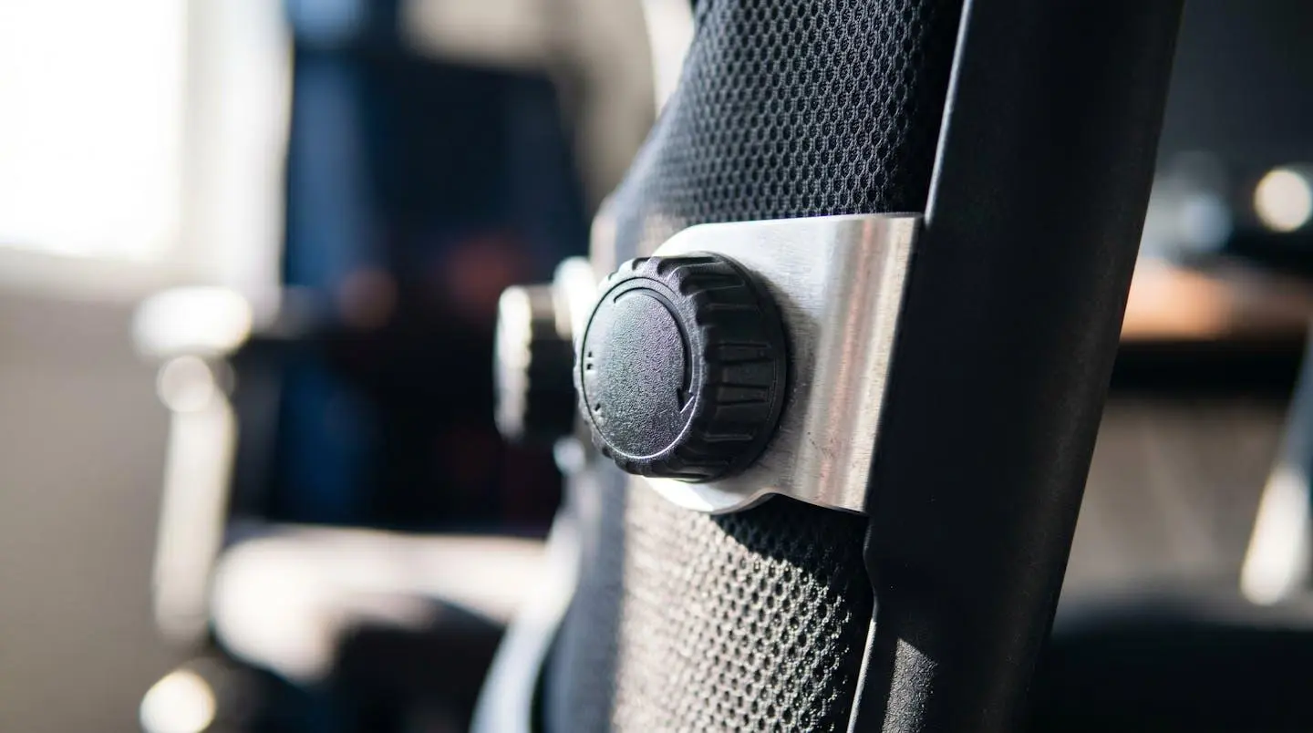 Gros plan sur le mécanisme de réglage du soutien lombaire d'un siège gaming moderne, avec molette de tension visible